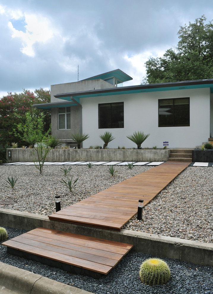 На фото: солнечный засухоустойчивый сад среднего размера на переднем дворе в стиле модернизм с покрытием из гравия и хорошей освещенностью
