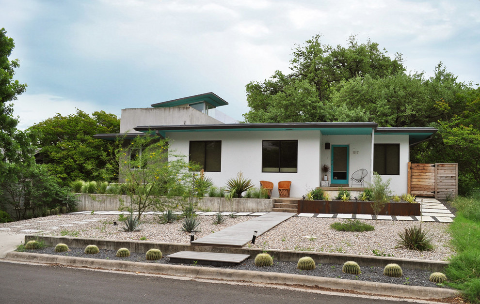 This is an example of a mid-sized mid-century modern drought-tolerant and full sun front yard gravel landscaping in Austin.