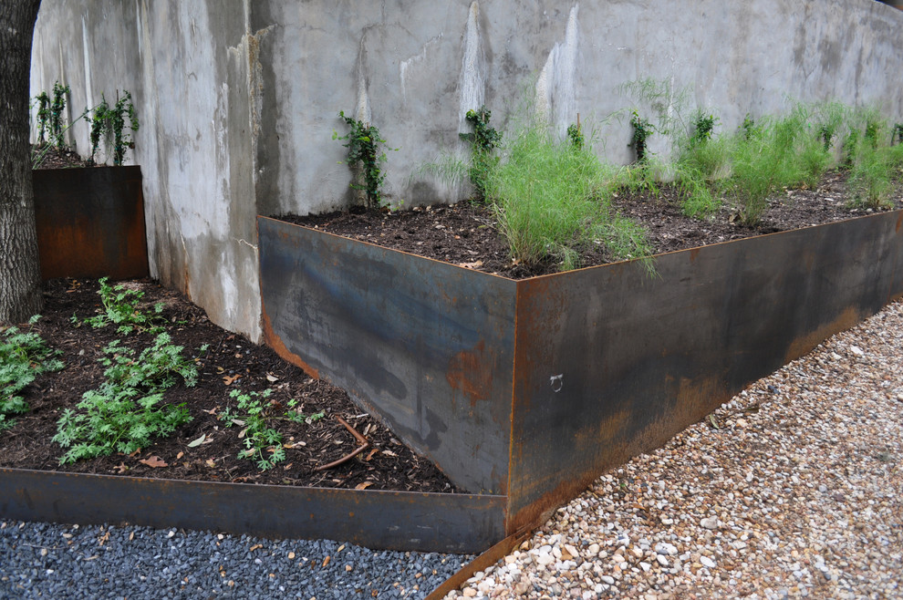 Photo of a large modern drought-tolerant and partial sun backyard gravel retaining wall landscape in Austin.