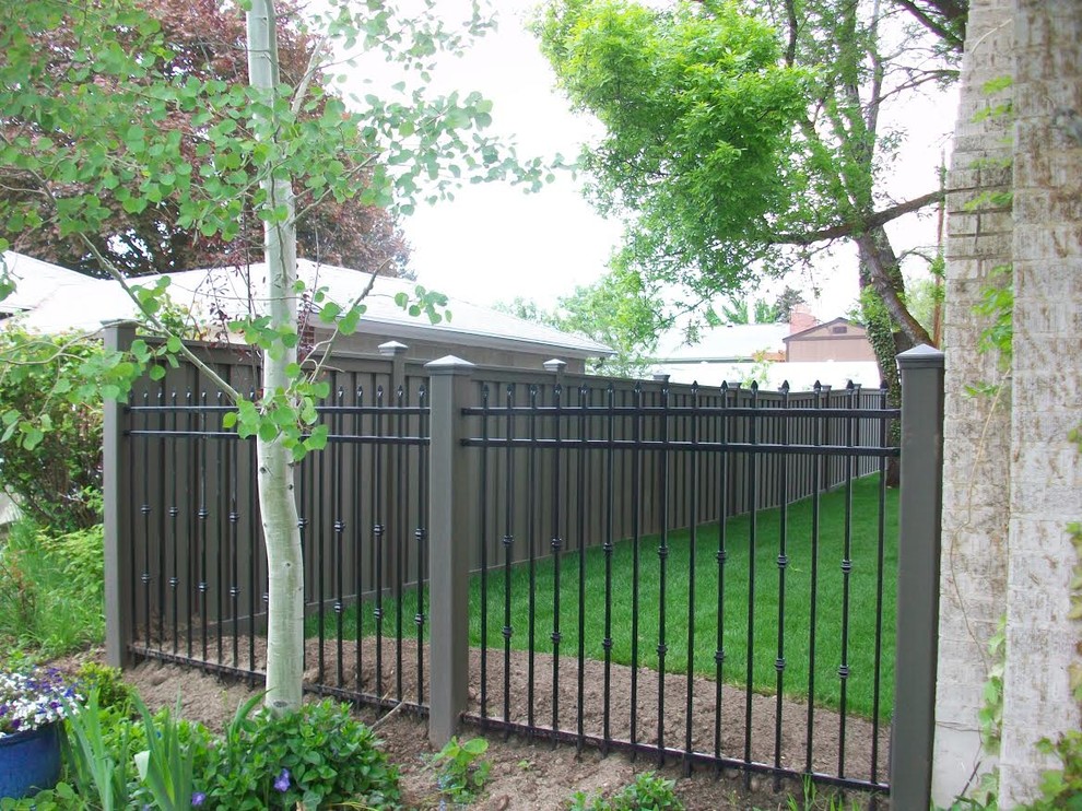 Large classic back fully shaded garden fence for spring in Los Angeles with mulch and a metal fence.
