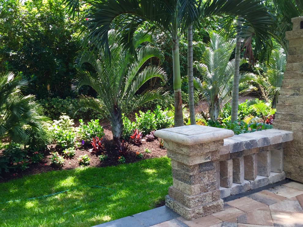 Photo of a mid-sized tropical partial sun backyard brick landscaping in Orlando.