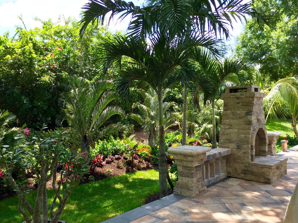 Cette photo montre un grand jardin arrière exotique avec une exposition partiellement ombragée et des pavés en brique.
