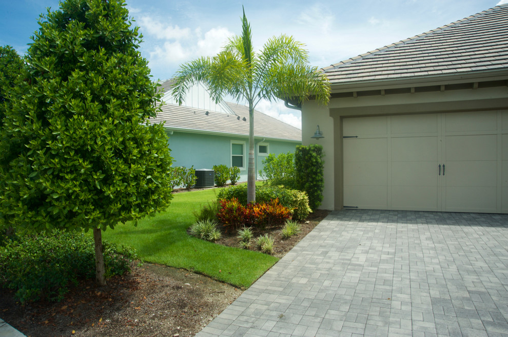 This is an example of a mid-sized tropical full sun front yard concrete paver driveway in Miami.