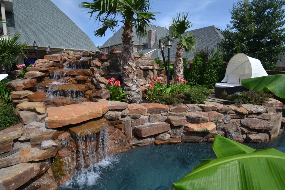Modelo de jardín exótico grande en patio trasero con fuente, exposición total al sol y adoquines de piedra natural