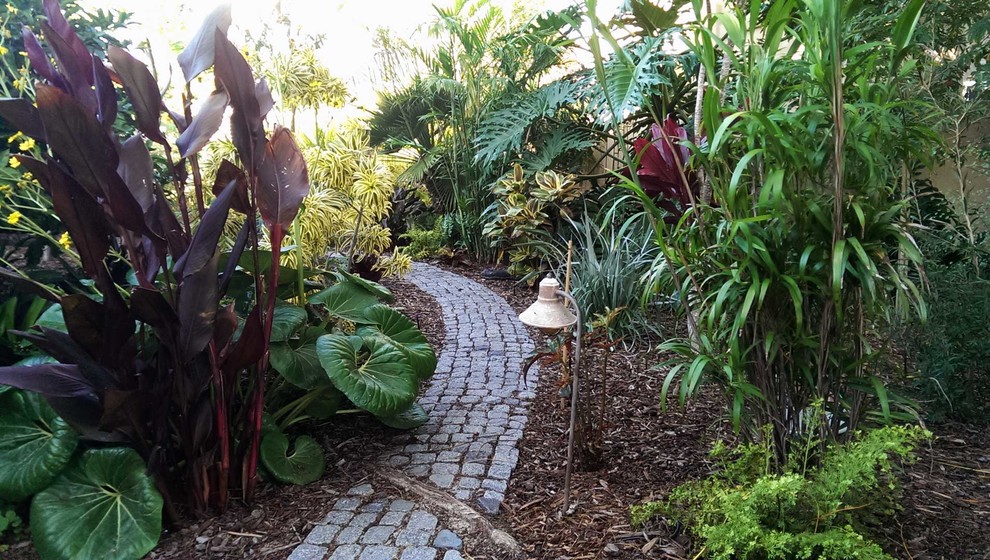 Inspiration for a large tropical partial sun backyard stone landscaping in San Diego.