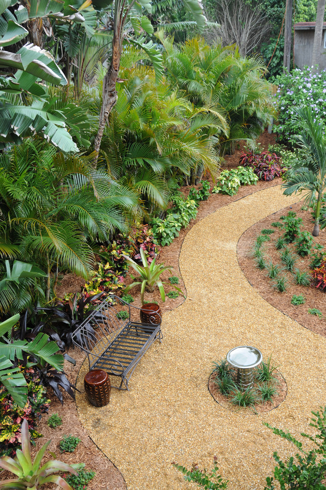 Foto di un grande giardino tropicale esposto in pieno sole dietro casa con ghiaia