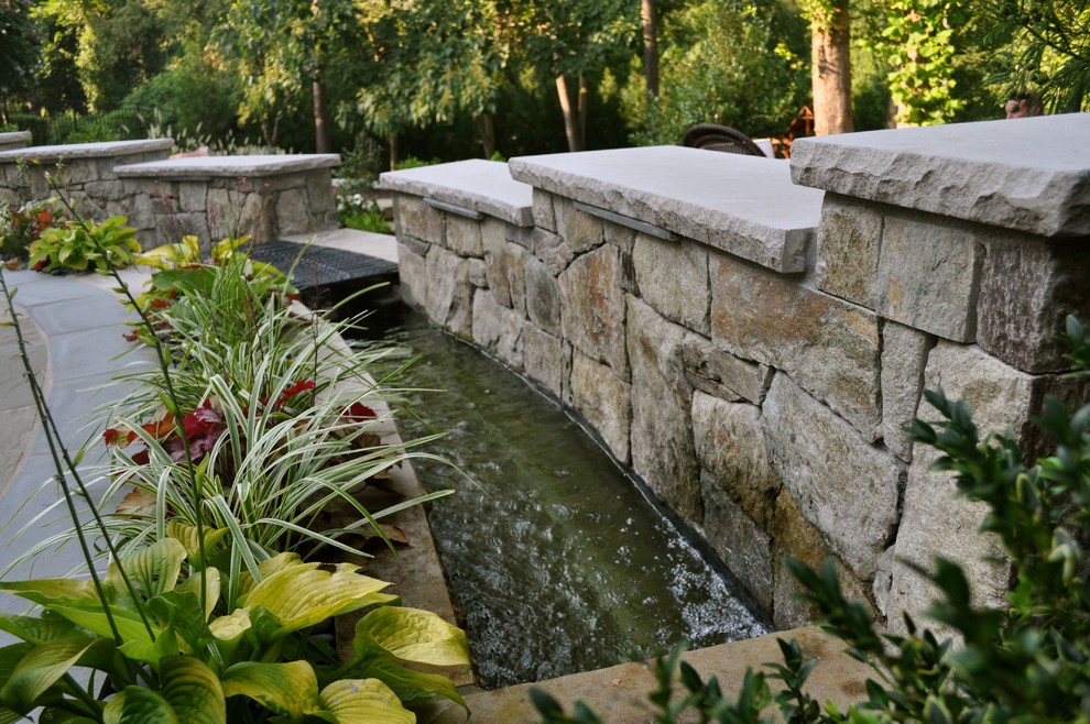 Cette image montre un jardin arrière traditionnel de taille moyenne avec un point d'eau, une exposition partiellement ombragée et des pavés en pierre naturelle.