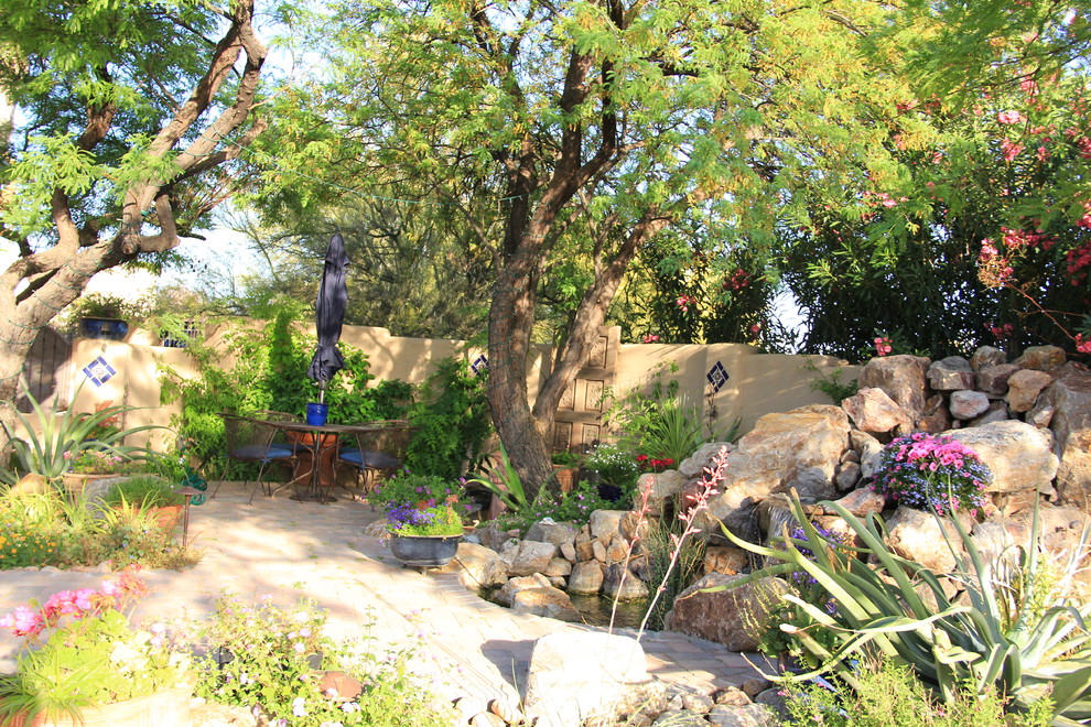 Immagine di un giardino xeriscape mediterraneo esposto a mezz'ombra di medie dimensioni e dietro casa in estate con fontane e pavimentazioni in mattoni