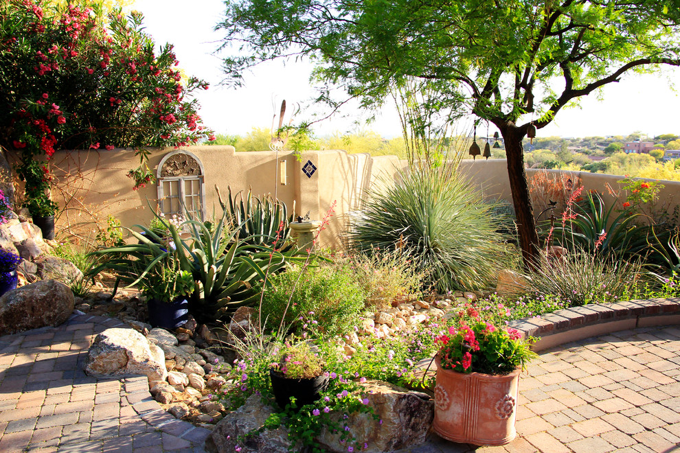 This is an example of a mid-sized mediterranean drought-tolerant, partial sun and desert backyard brick landscaping in Phoenix for summer.