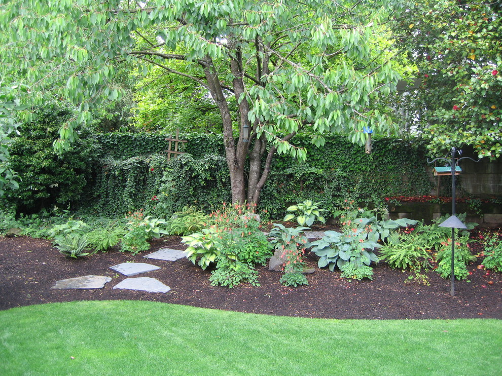 Cette image montre un jardin à la française arrière traditionnel de taille moyenne et l'été avec une exposition ombragée et un paillis.