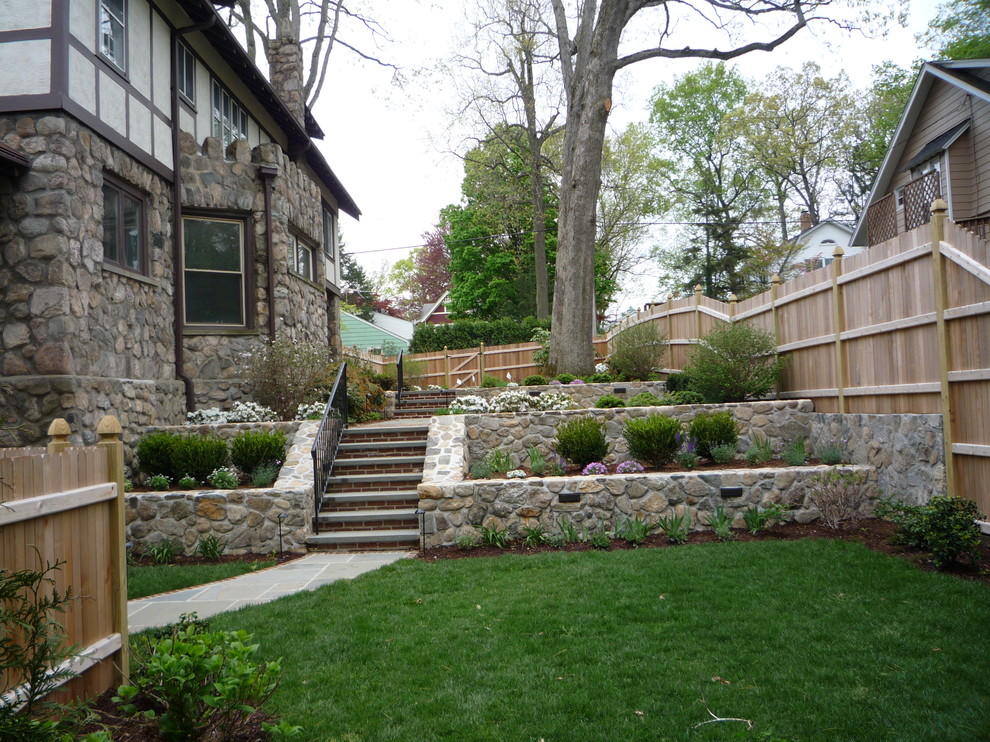 Пример оригинального дизайна: тенистый участок и сад среднего размера на заднем дворе в стиле кантри с подпорной стенкой и покрытием из каменной брусчатки