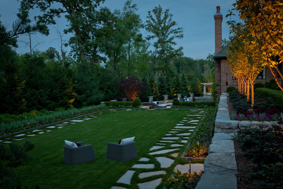 Diseño de jardín clásico renovado grande en patio trasero con adoquines de piedra natural