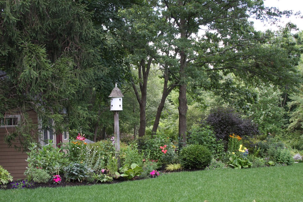 Cette image montre un grand jardin arrière traditionnel l'été avec une exposition ensoleillée et des pavés en pierre naturelle.