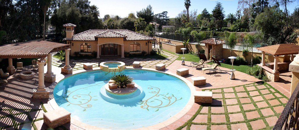 Expansive mediterranean back full sun garden in Los Angeles with a fire feature and natural stone paving.