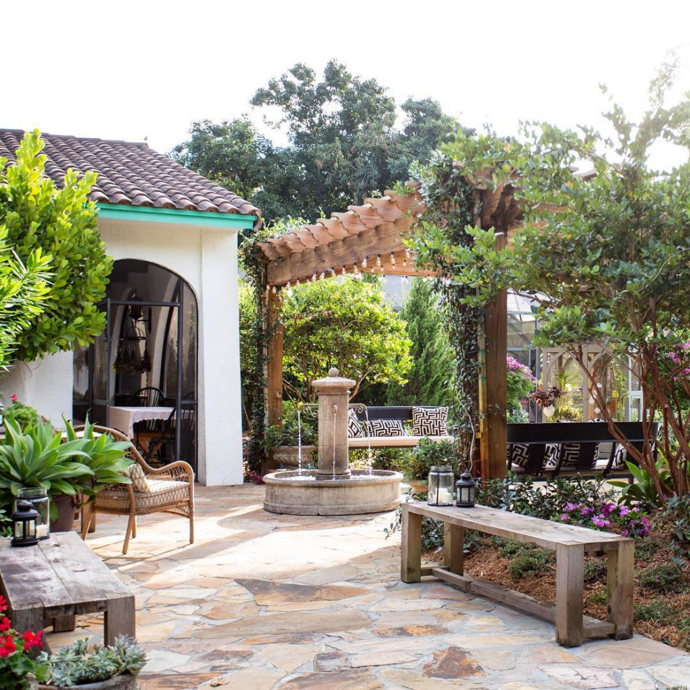 This is an example of a large rural front patio in Miami with a water feature and natural stone paving.