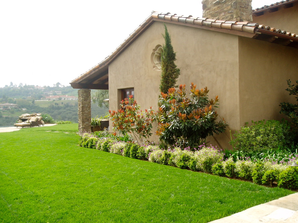На фото: большой солнечный участок и сад на заднем дворе в средиземноморском стиле с хорошей освещенностью и покрытием из каменной брусчатки