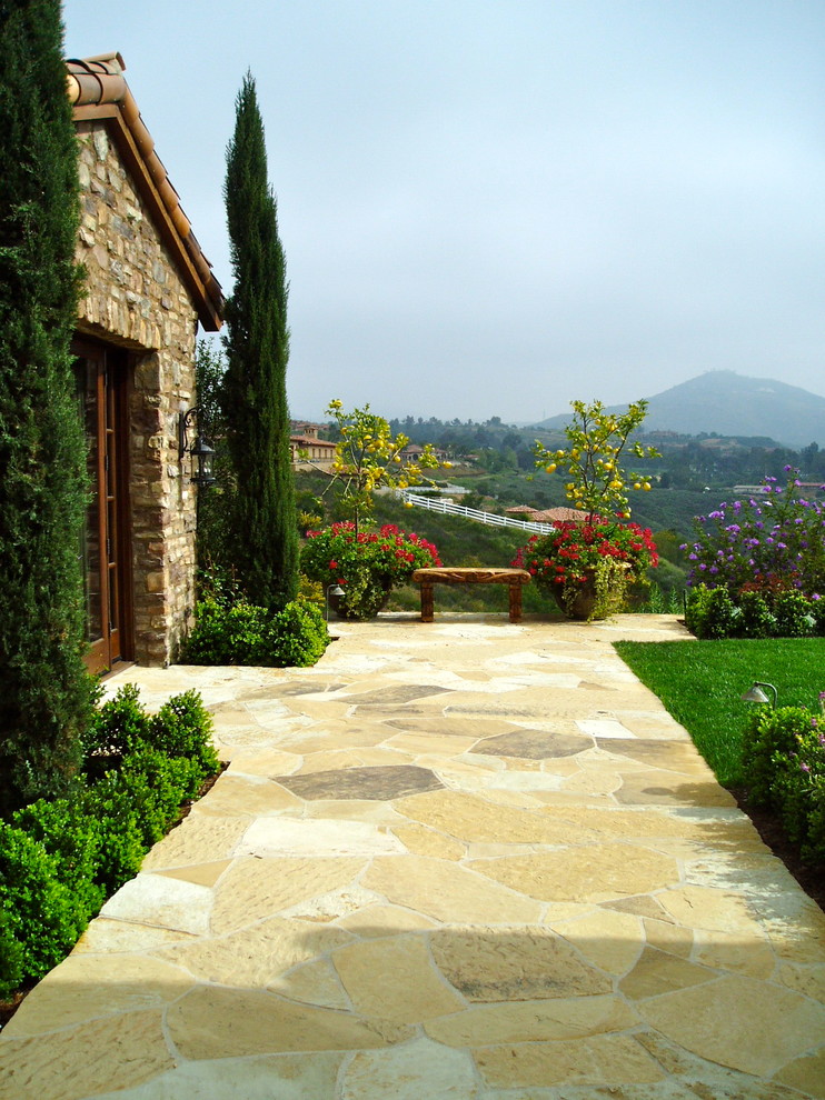 Großer Mediterraner Garten hinter dem Haus mit direkter Sonneneinstrahlung und Natursteinplatten in San Diego