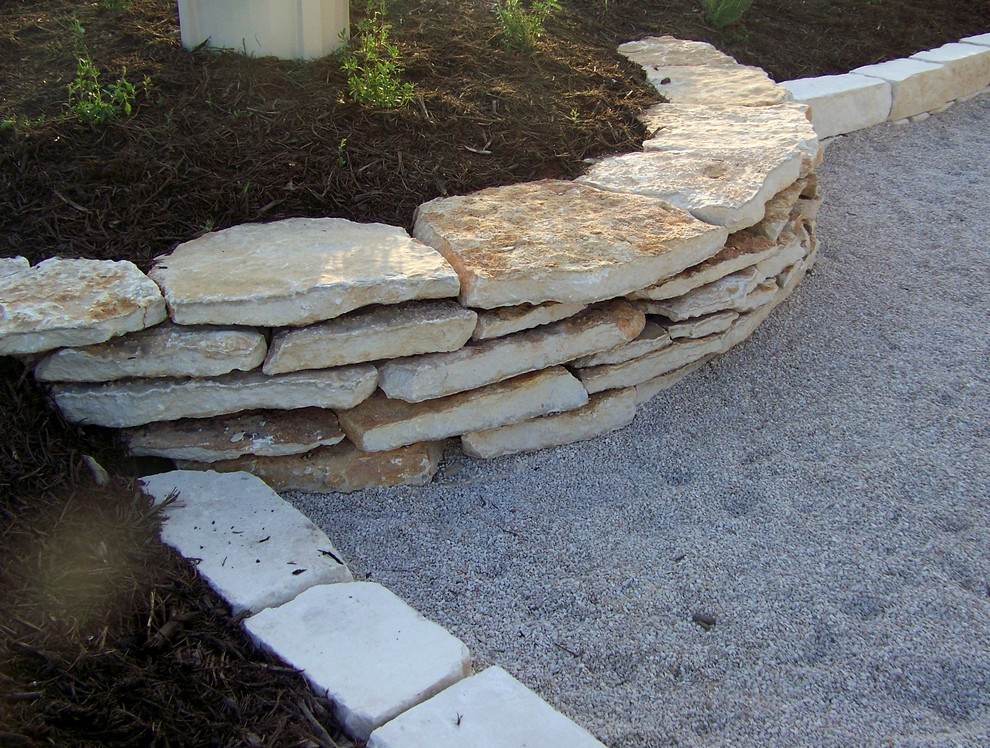 Photo of a mediterranean partial sun side yard stone retaining wall landscape in Austin.