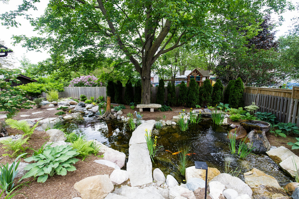 Inspiration pour un grand jardin arrière traditionnel avec un bassin et des pavés en pierre naturelle.