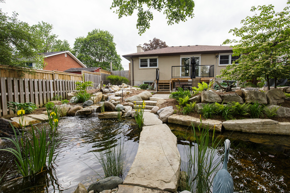 This is an example of a large transitional backyard stone pond in Toronto.