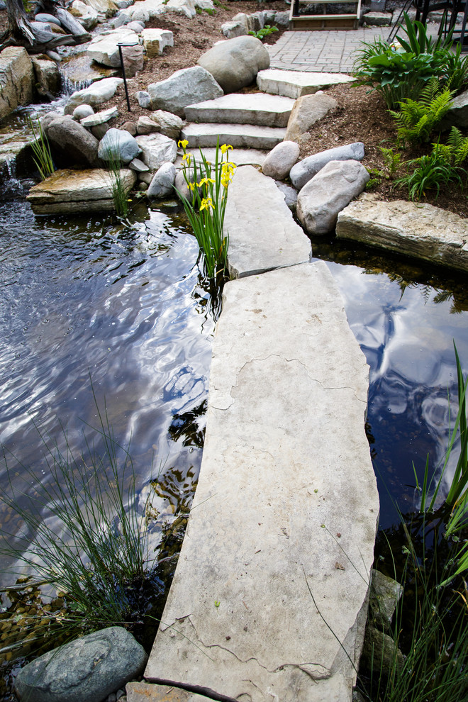 Ejemplo de jardín tradicional renovado grande en patio trasero con estanque y adoquines de piedra natural