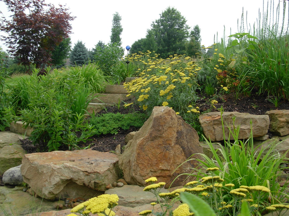 Foto de jardín clásico de tamaño medio en verano en patio trasero con fuente, exposición total al sol y adoquines de piedra natural