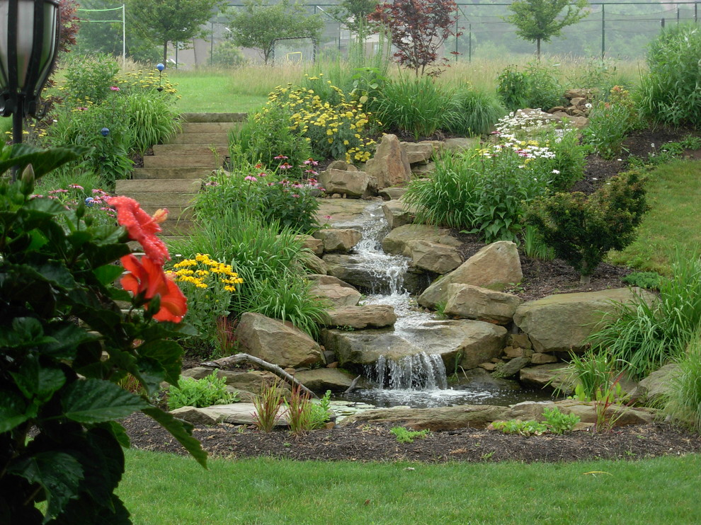 Immagine di un piccolo giardino tradizionale esposto in pieno sole dietro casa in estate con fontane e pavimentazioni in pietra naturale