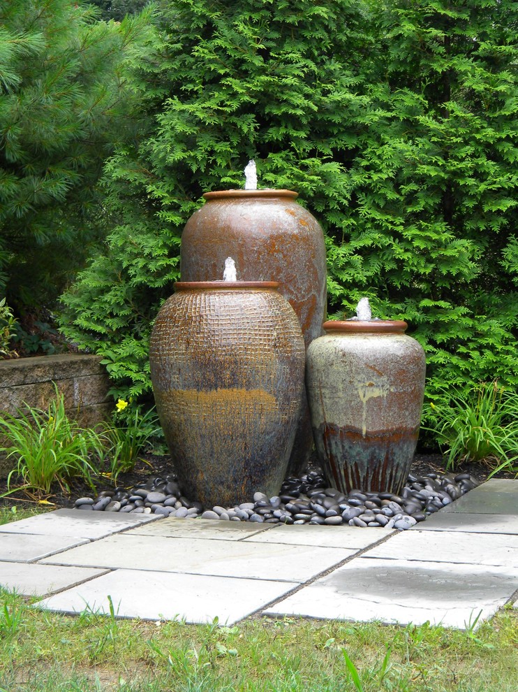 This is an example of a mid-sized traditional full sun backyard stone water fountain landscape in Other for summer.