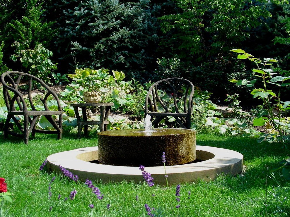 Diseño de jardín clásico de tamaño medio en verano en patio trasero con fuente, exposición total al sol y mantillo
