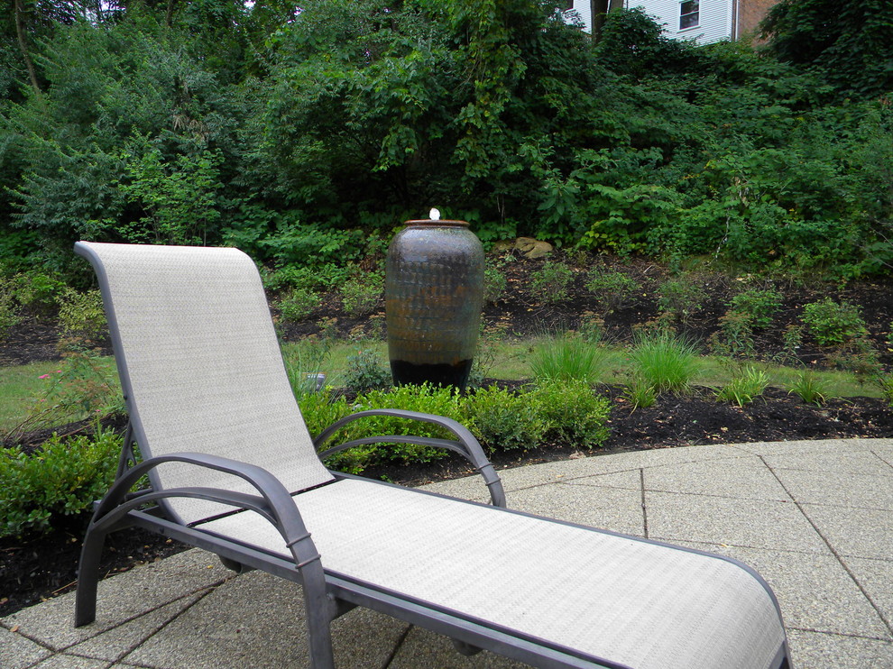 Imagen de jardín clásico de tamaño medio en verano en patio trasero con fuente y exposición total al sol
