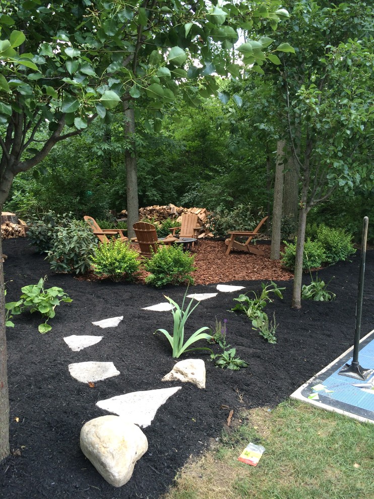 Photo of a mid-sized traditional shade backyard stone landscaping in Columbus with a fire pit.