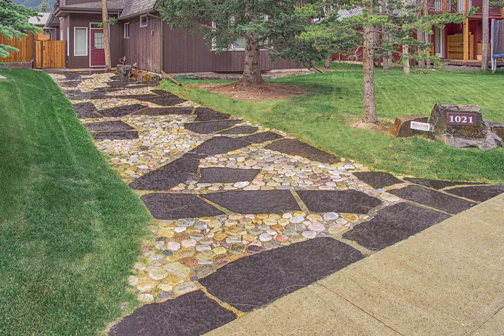Photo of a mid-sized contemporary full sun front yard stone driveway in Calgary for fall.