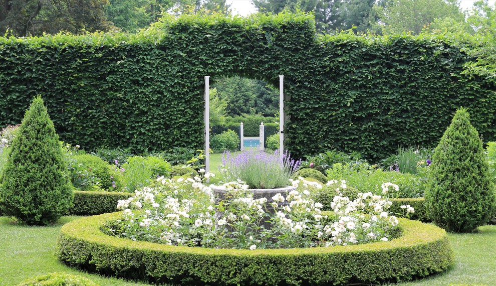 Foto di un ampio giardino vittoriano esposto in pieno sole dietro casa in estate con un ingresso o sentiero