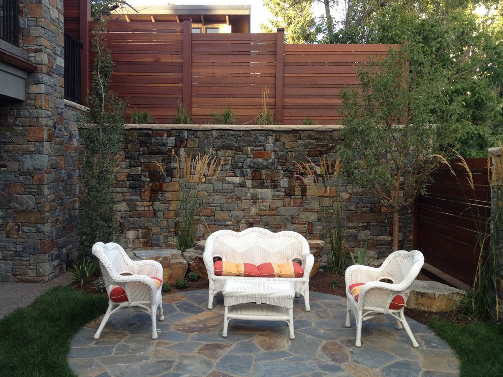 Medium sized traditional back garden in Calgary with a retaining wall and concrete paving.