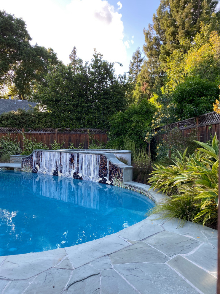 Foto de piscina clásica renovada de tamaño medio en patio trasero con adoquines de hormigón