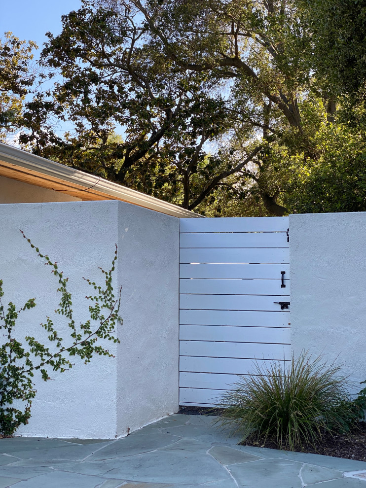На фото: регулярный сад среднего размера на заднем дворе в стиле неоклассика (современная классика) с покрытием из каменной брусчатки и воротами с