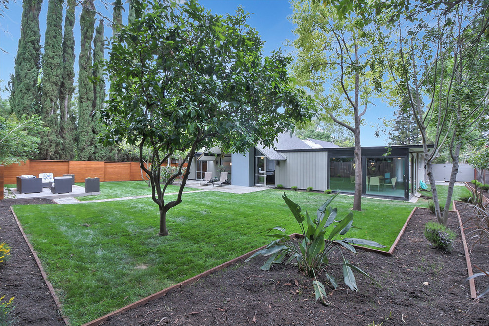 На фото: большой участок и сад на заднем дворе в стиле ретро с полуденной тенью и мощением тротуарной плиткой