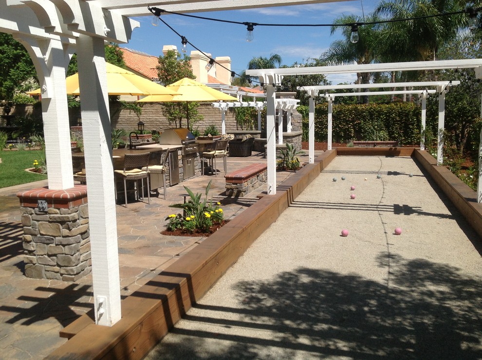 This is an example of a large traditional full sun backyard stone water fountain landscape in Los Angeles with a pergola.