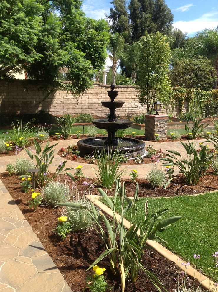 Ispirazione per un grande giardino chic esposto in pieno sole dietro casa con pavimentazioni in pietra naturale e fontane