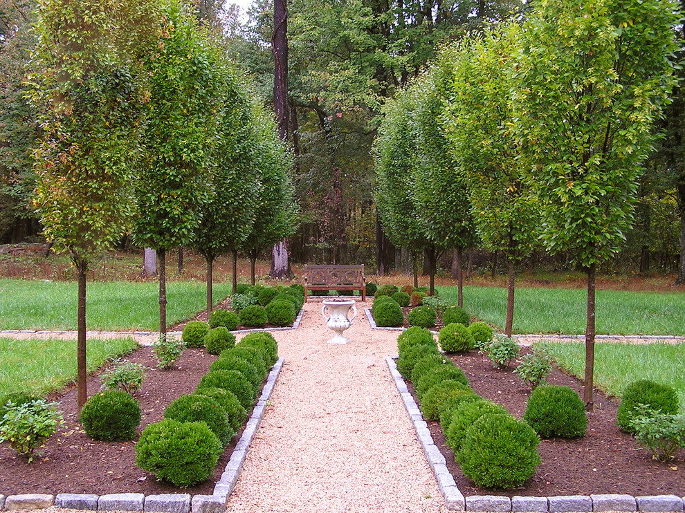 Exempel på en stor trädgård i full sol, med en stödmur och naturstensplattor