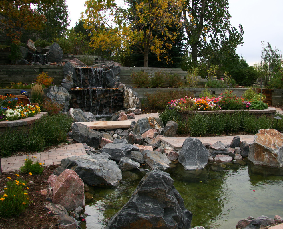 Inspiration for a large classic back xeriscape full sun raised pond for summer in Denver with a pond and brick paving.