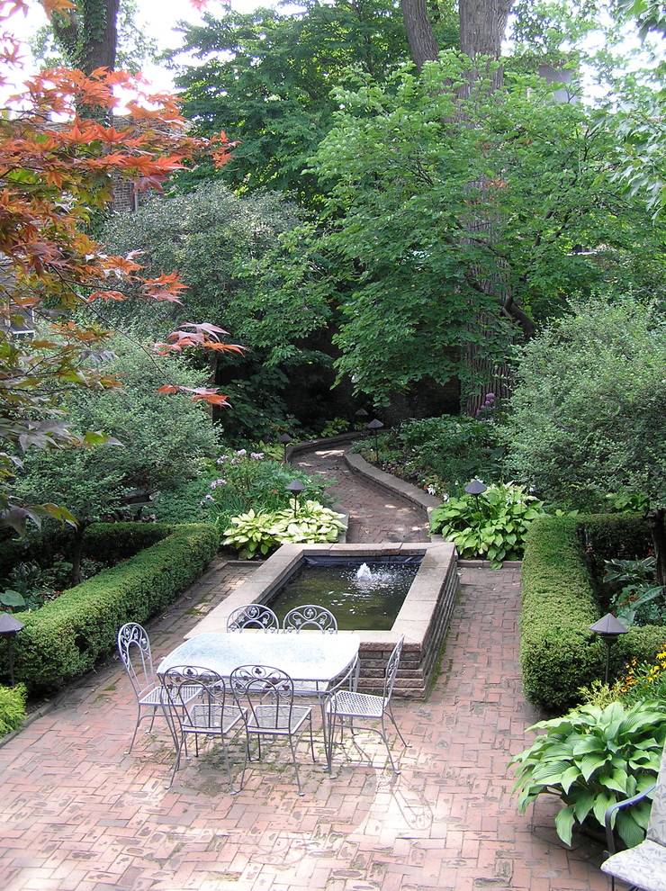 Esempio di un giardino classico esposto a mezz'ombra dietro casa con un ingresso o sentiero e pavimentazioni in mattoni