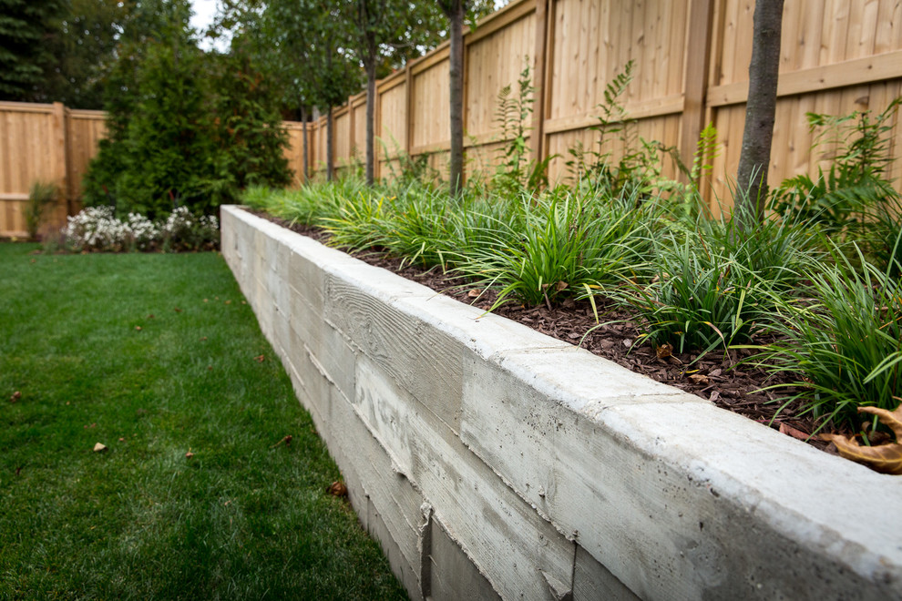 Inspiration for a small contemporary back partial sun garden in Grand Rapids with a retaining wall and mulch.