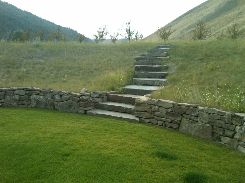 Foto di un ampio giardino country esposto in pieno sole con un muro di contenimento, un pendio, una collina o una riva e pavimentazioni in pietra naturale