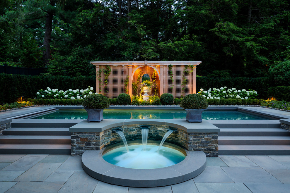 Immagine di una piscina chic di medie dimensioni e dietro casa con pavimentazioni in pietra naturale e fontane