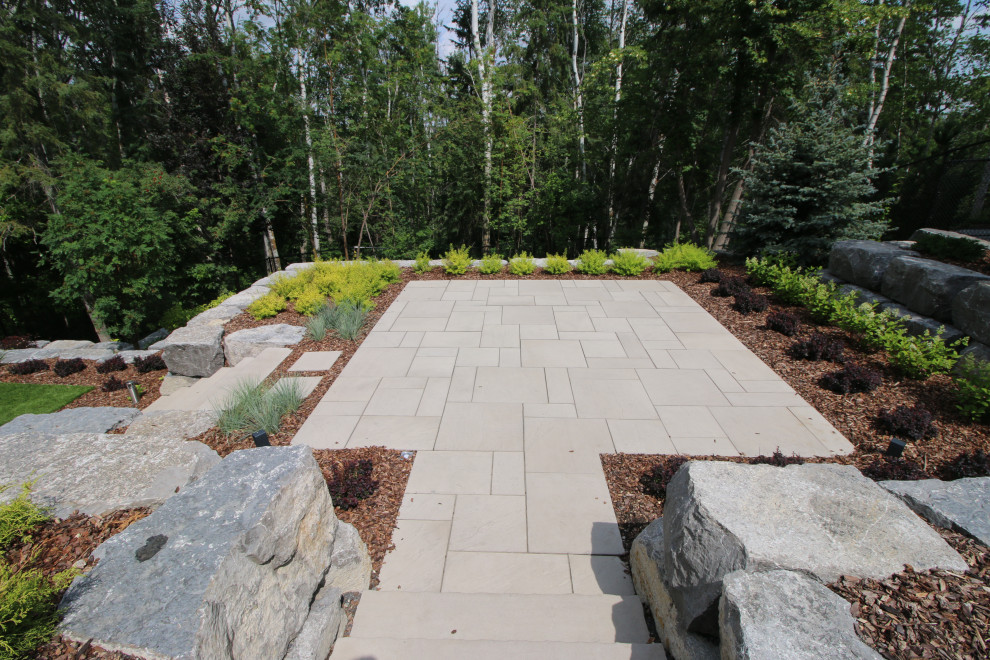This is an example of a large contemporary back formal garden in Edmonton with natural stone paving.