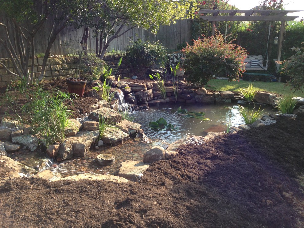 Inspiration for a large traditional partial sun backyard stone pond in Dallas.