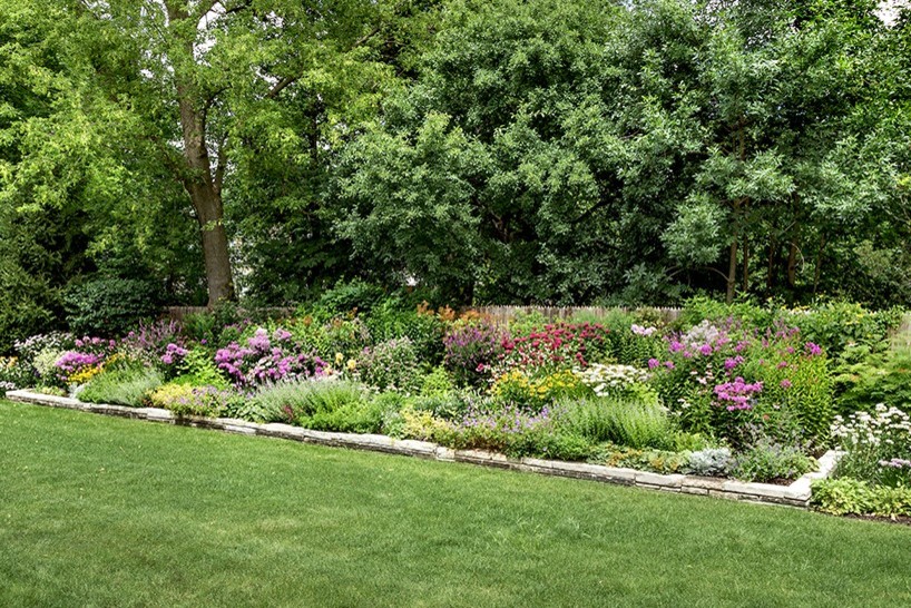 Modelo de jardín clásico de tamaño medio en verano en patio trasero con exposición total al sol