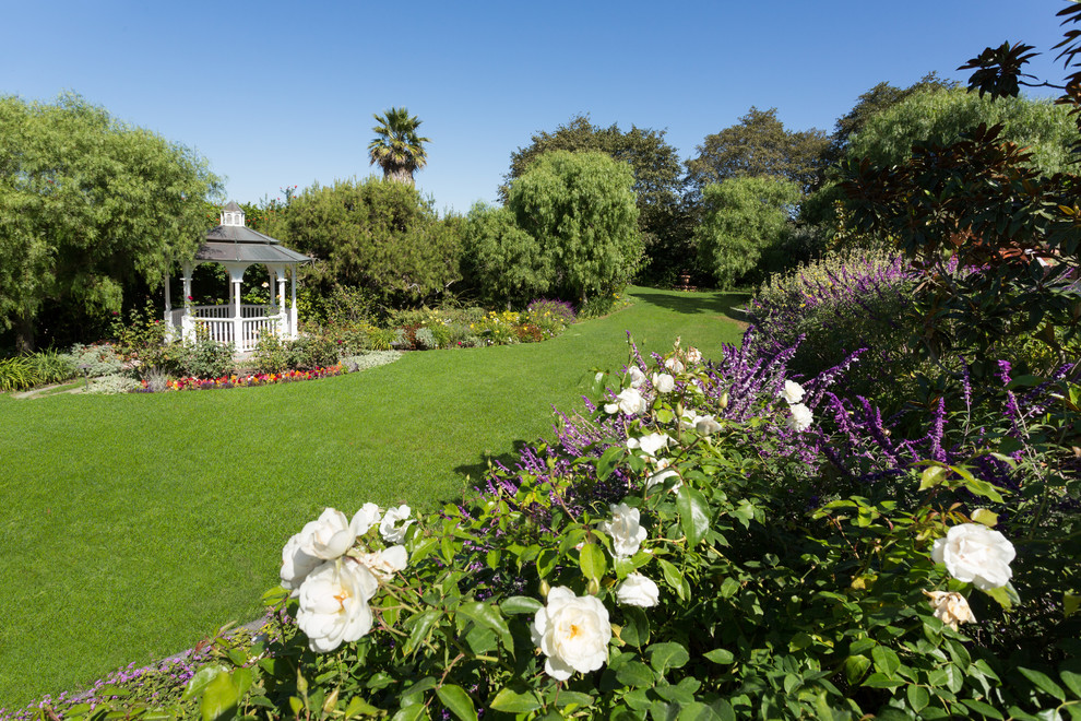 Imagen de jardín tradicional extra grande en primavera en patio trasero con jardín francés, exposición total al sol y mantillo