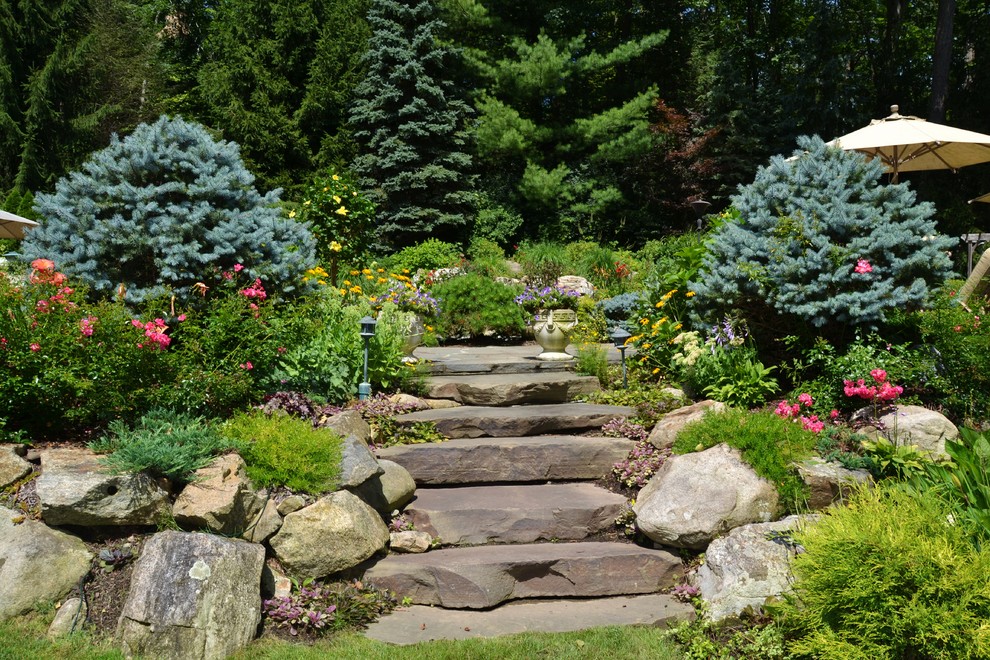 Réalisation d'un jardin tradition avec une pente, une colline ou un talus et des pavés en pierre naturelle.